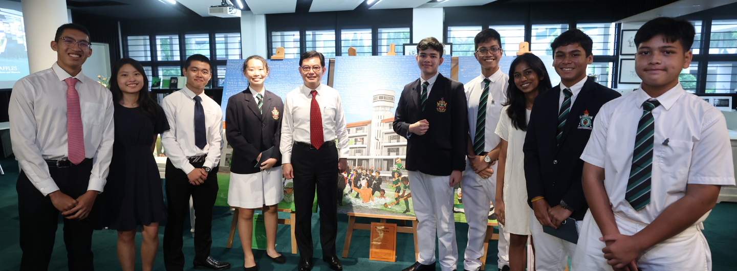 Group of people posing in front of Raffles Institution artwork.